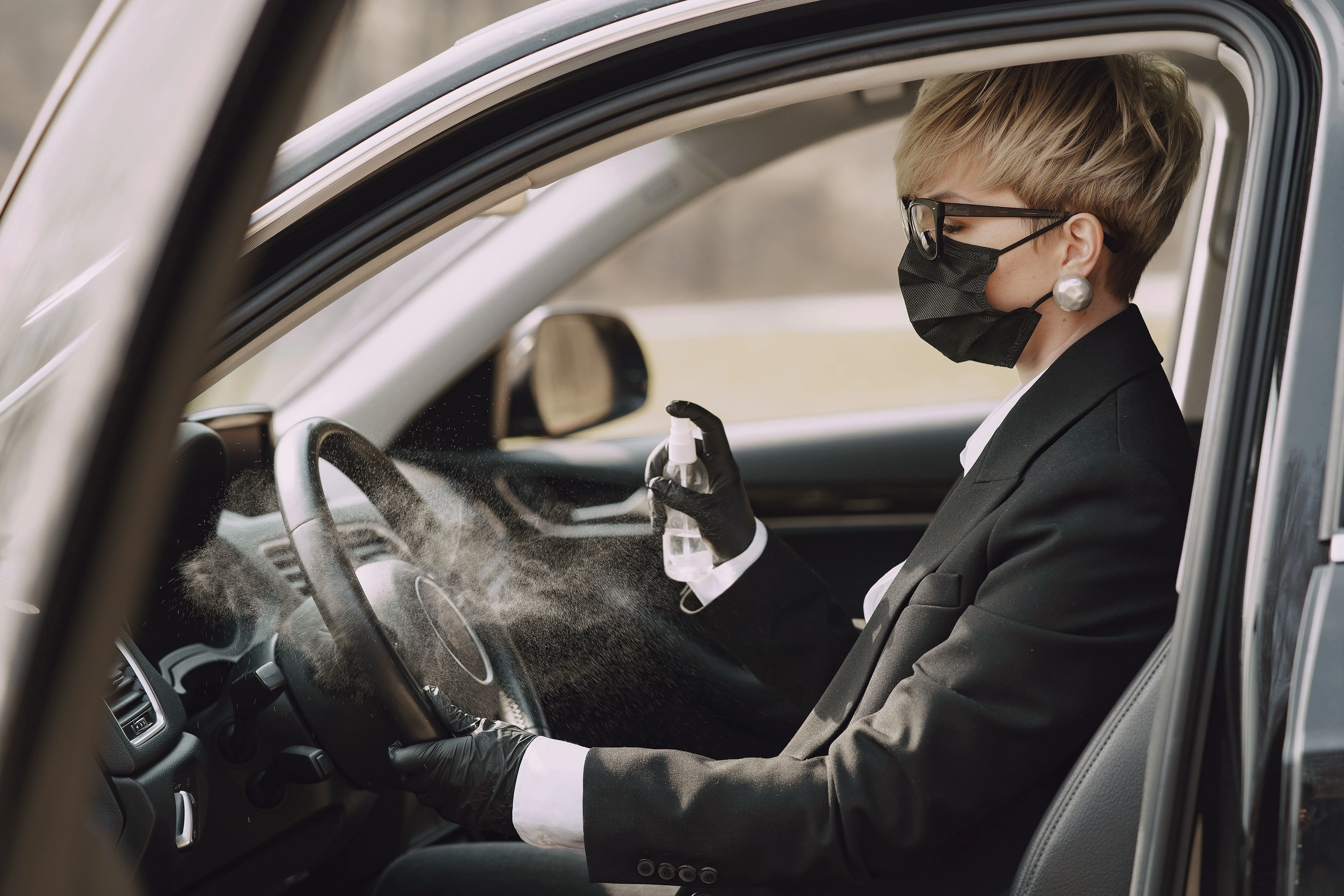A woman sprays sanitizer inside a car to eliminate the bad smell from the interior