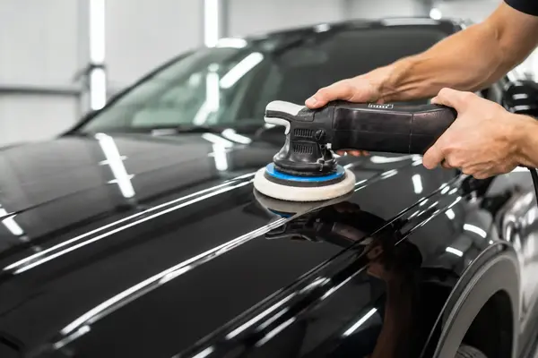 Worker Polishing a White Hatchback